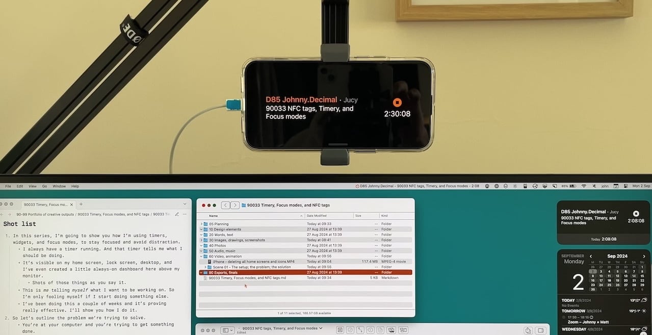 A picture of an iPhone on a microphone mount 'floating' above my monitor. On it is a timer, that tells me I should be working on activity '90033 NFC tags, Timery, and Focus modes' – which is the video I'm talking about in this post.