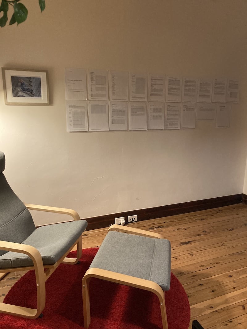 A photograph of our old lounge room wall. There are 20 sheets of printed business plan template stuck to it.