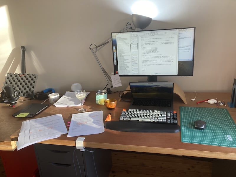 A photo of my desk on a Friday evening. The late-day sun lights the scene. On the desk is a gin martini.