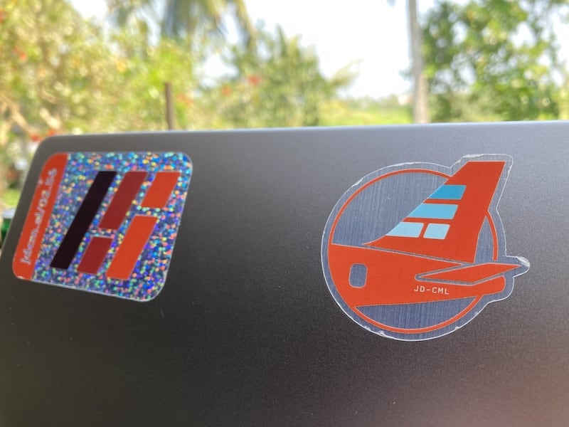 A photo of our sticker on the back of a laptop. It's in the shape of an airplane's tail fin. The aircraft's registration is JD-CML.